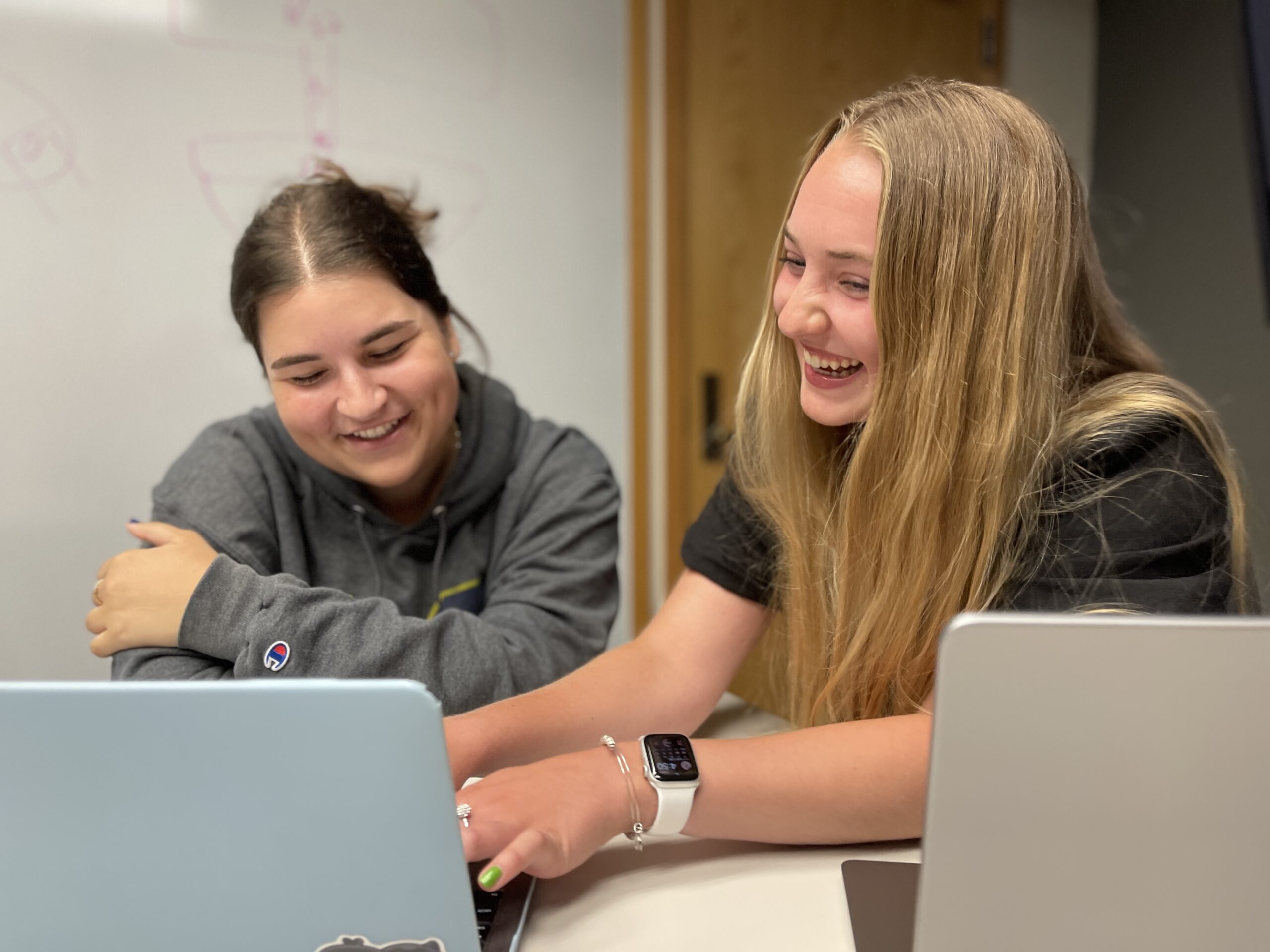 Maddy Heyer smiles while using a computer beside another CHEPS student.