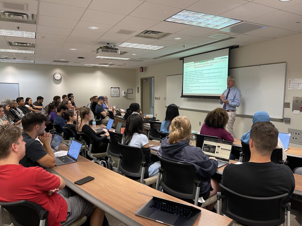 Andrew Fine presents to a classroom full of seminar attendees.