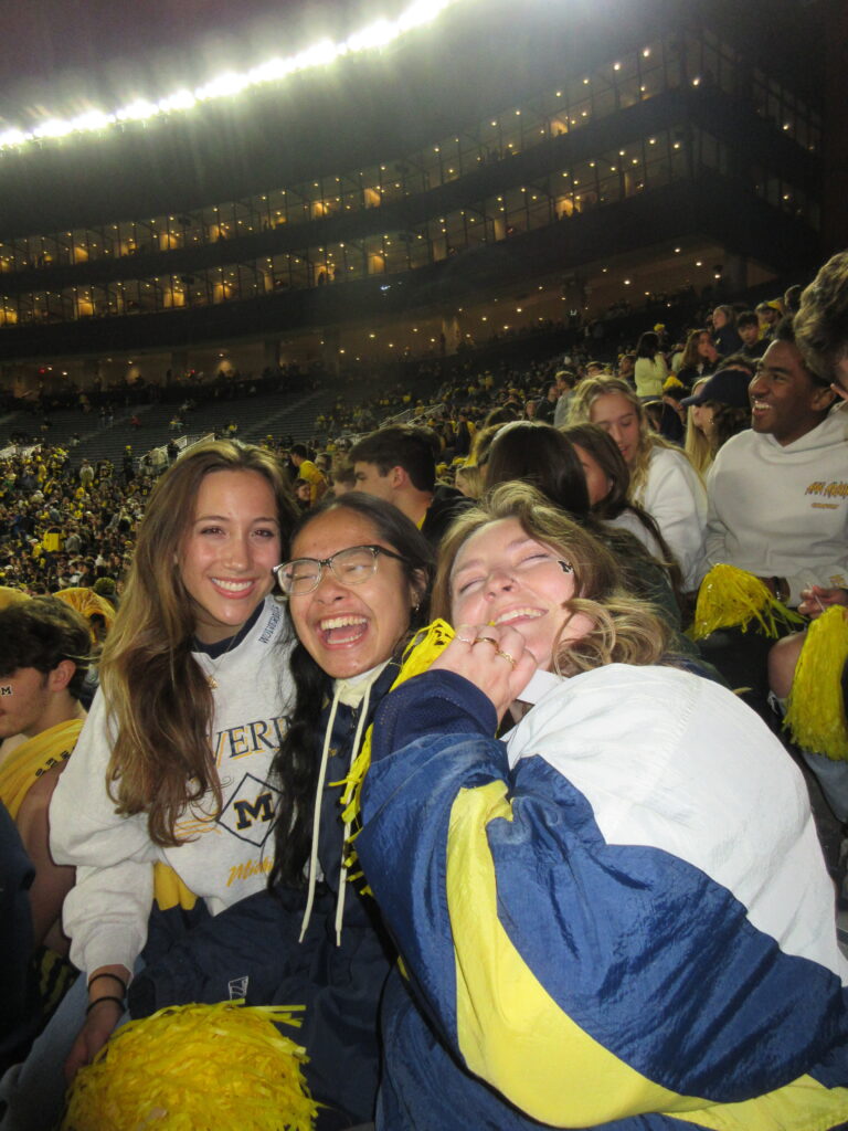 Jill, Goretti, and Nikki cheering the Wolverines to victory against Michigan State.